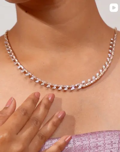 A diamond line necklace worn at the collarbone.