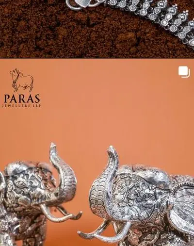 A pair of carved silver elephants with roses scattered around.