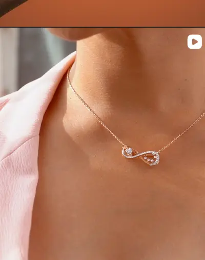 A fine chain with a diamond infinity pendant, worn.
