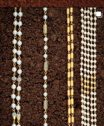 Four fine pearl and gold chains laid on brown earth.