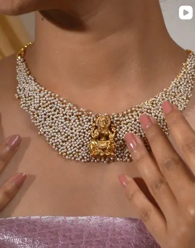 A pearl cluster choker with a gold Lakshmi pendant, worn.