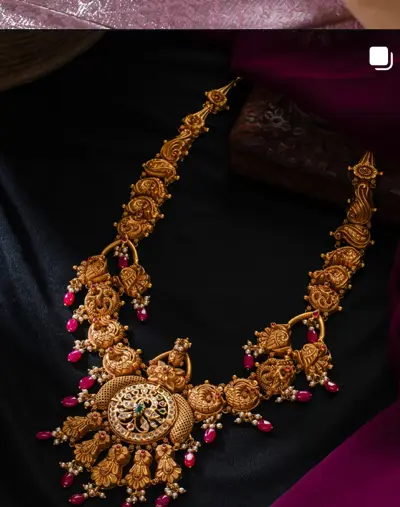A gold temple haram with ruby beads and a broad central pendant.