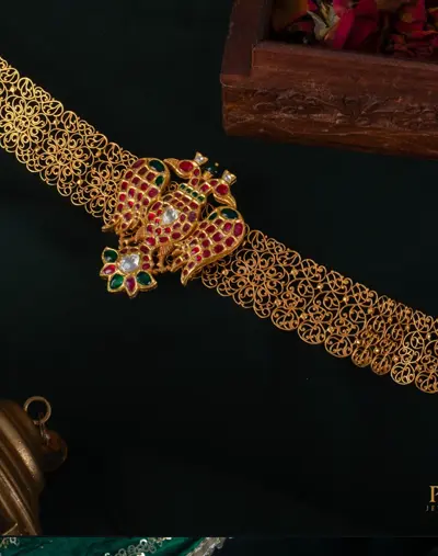 A filigree gold vaddanam waist belt with a kemp set clasp.